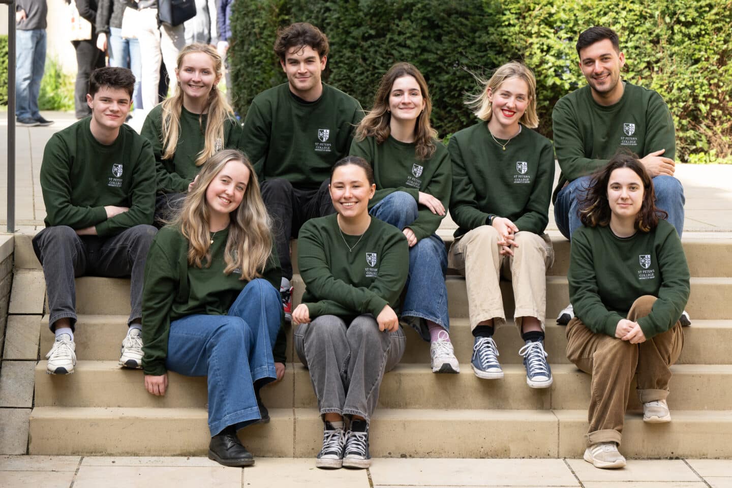 A group of young people seated on steps and smiling