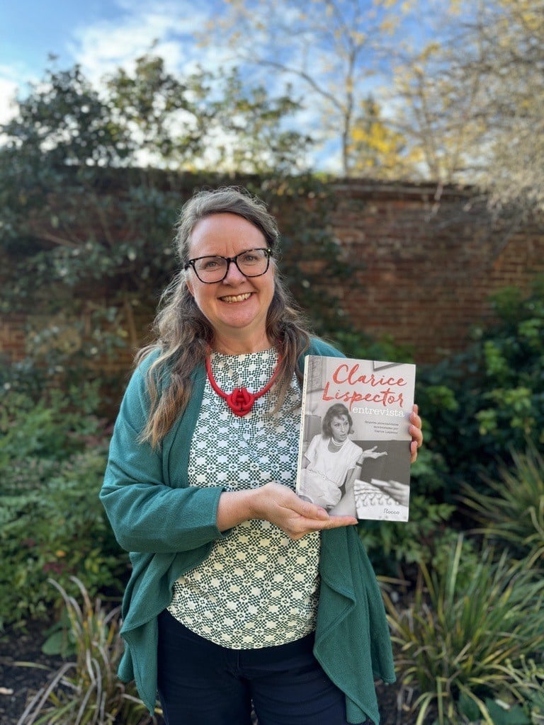 Claire Williams holding a book and standing outdoors