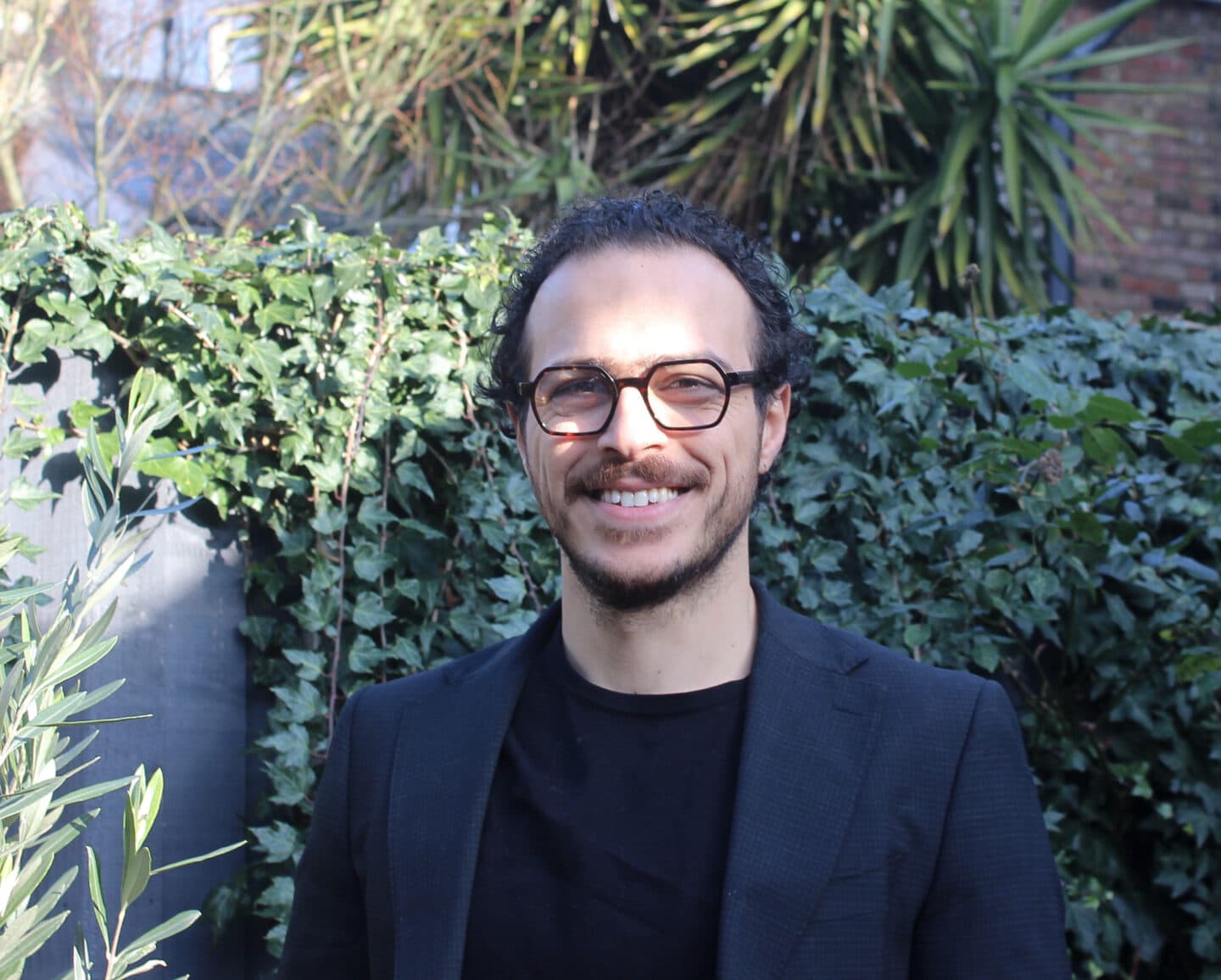 A man wearing glasses and a blazer