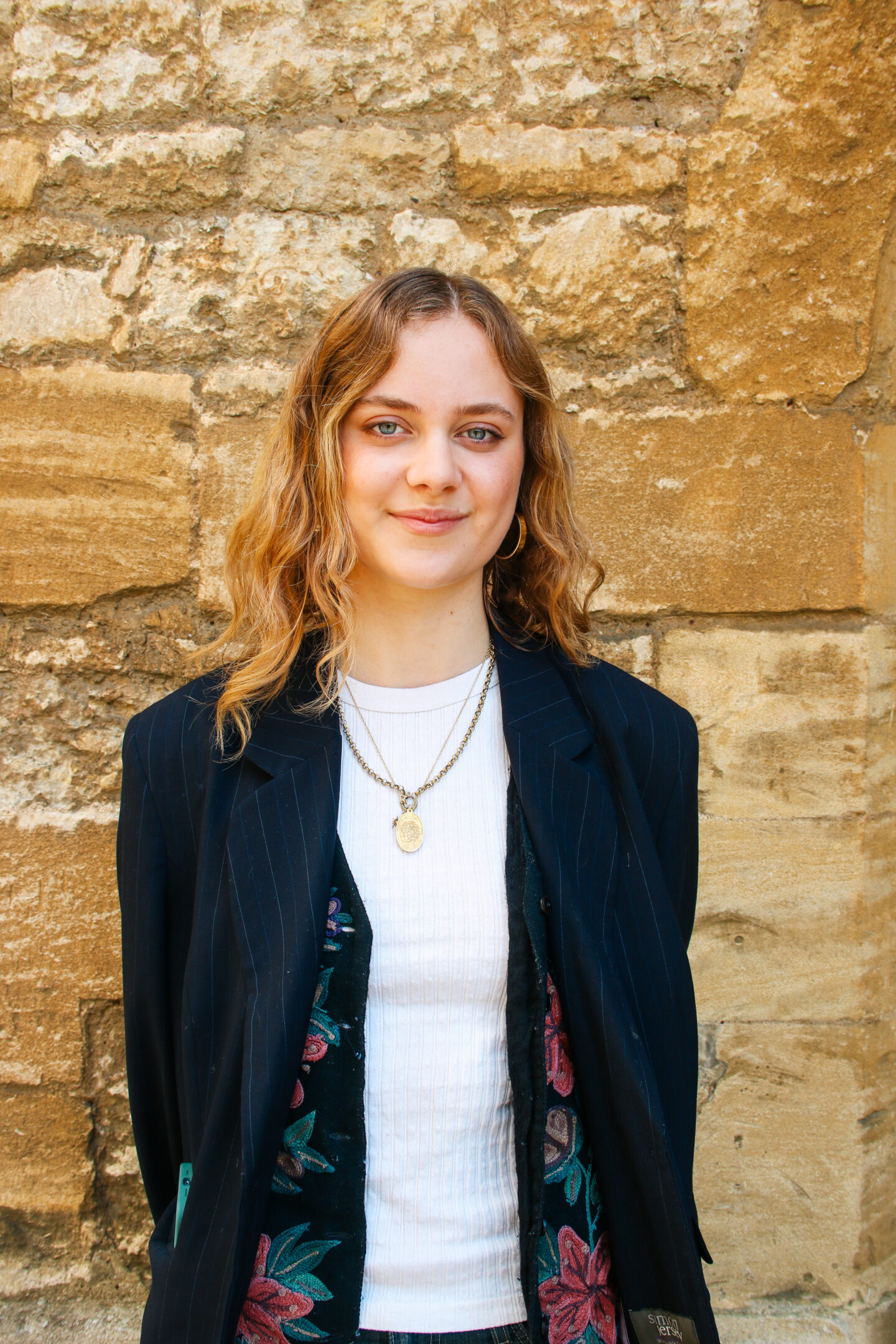A headshot of student Aneshka Moudry standing in front of a stone wall