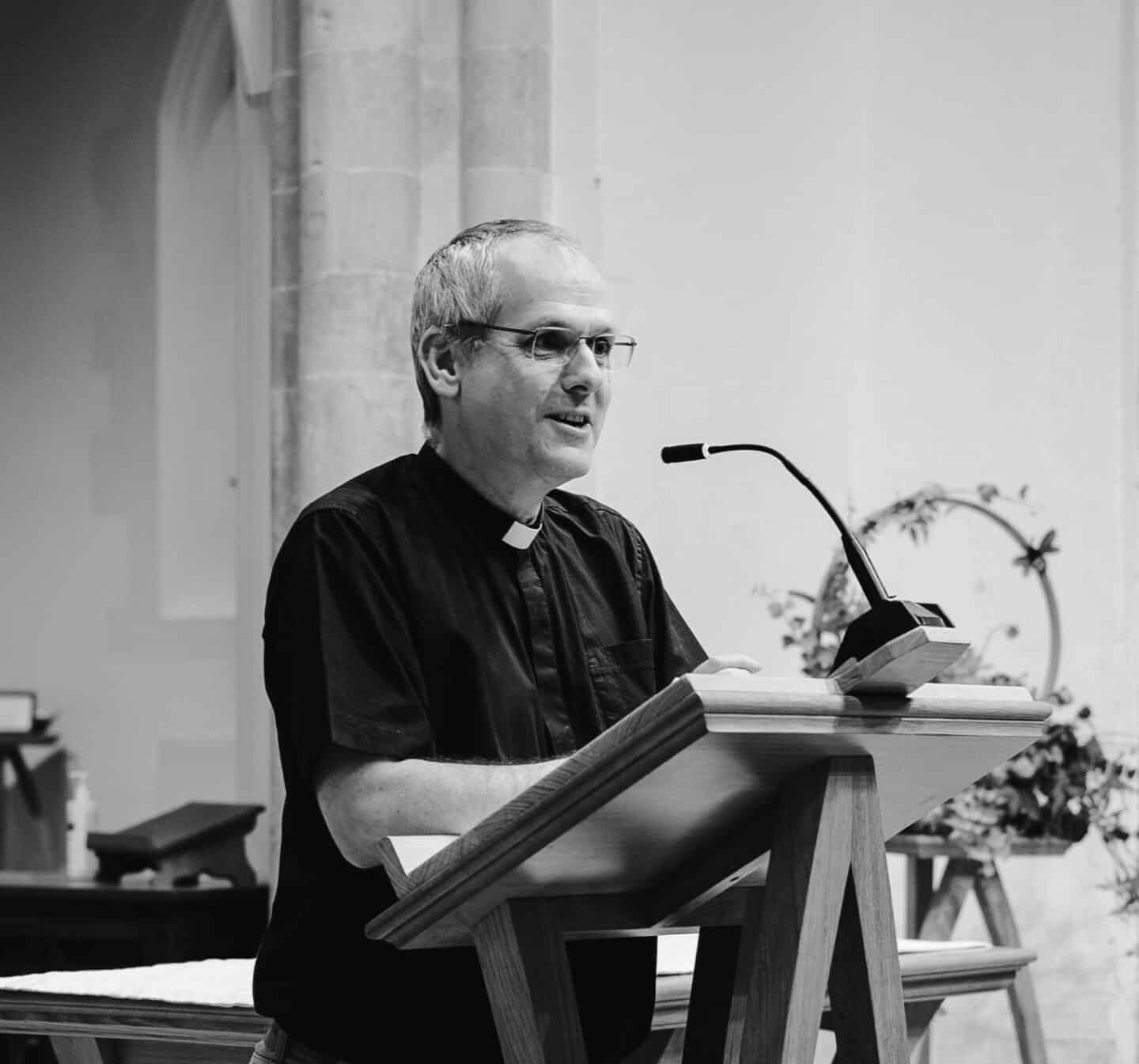 Matthew Routledge - a man wearing clerical collar speaking at a lectern