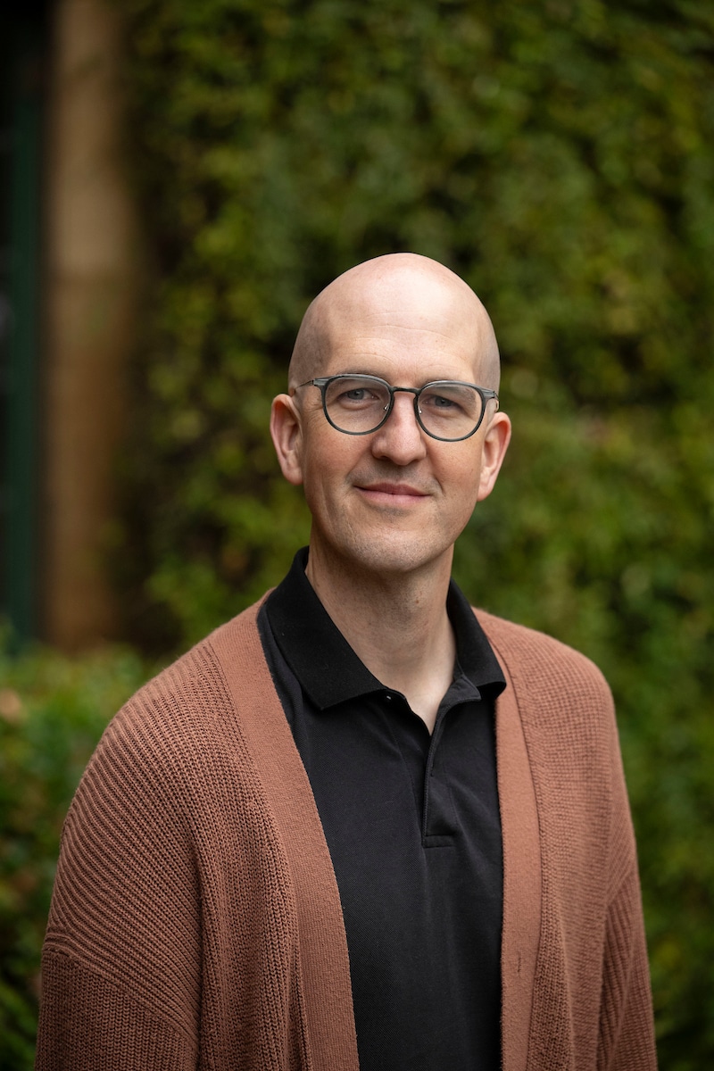 Matthew Fuchter - a man wearing glasses, black shirt and brown cardigan