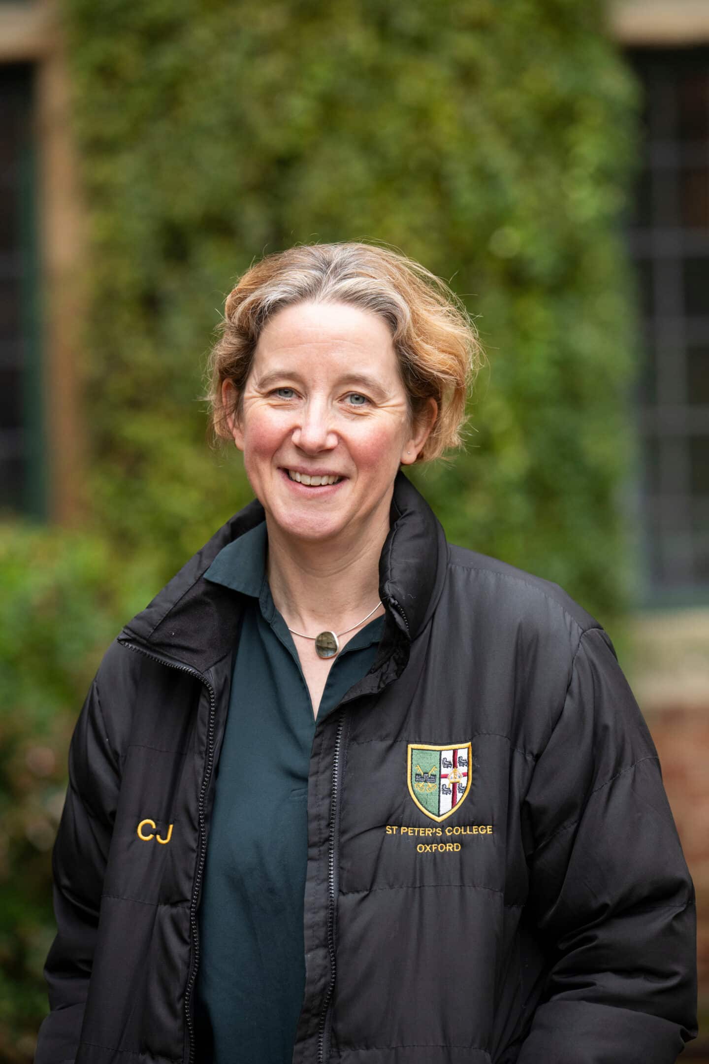 A woman wearing a green top and puffer jacket and standing outdoors
