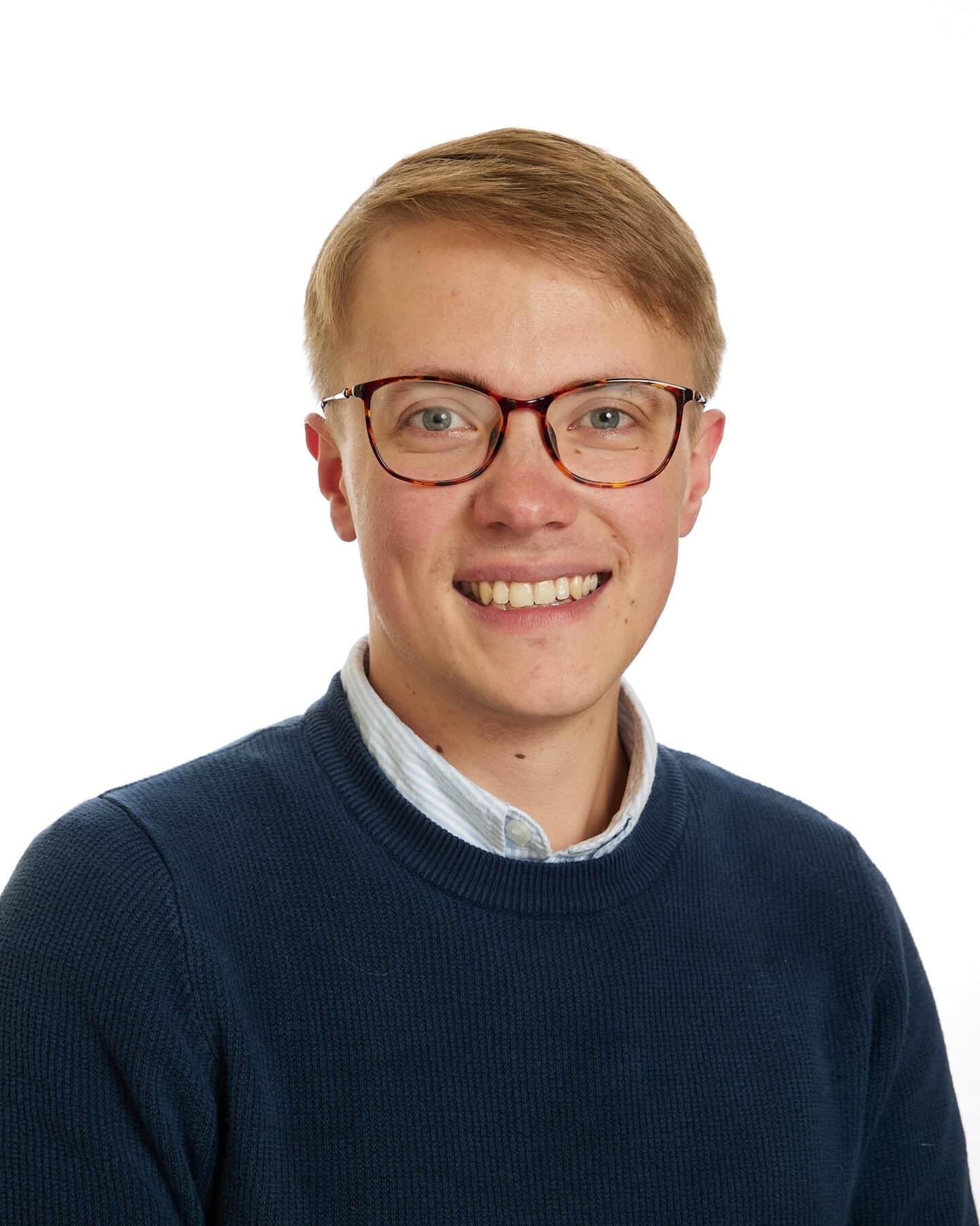 A headshot of a person with red hair and glasses