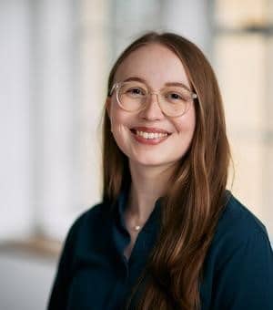 Clara Schreiner headshot -- a person with long hair wearing glasses and smiling